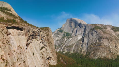 slow motion approach to the cliffs in yosemite national park, california, usa. pine tree wood growing at the foot of mountain.