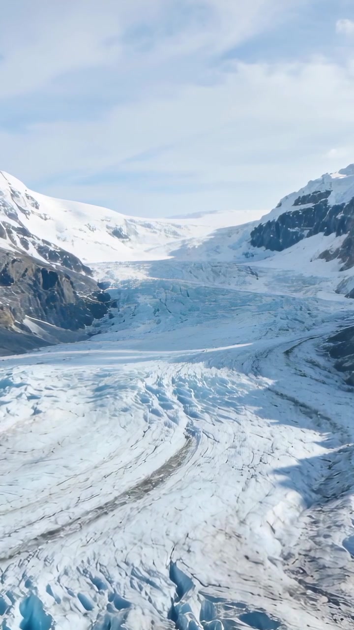 Vertical video: Advancing drone revealing glacier tongue crevasses blue ice and moraine in U-valley