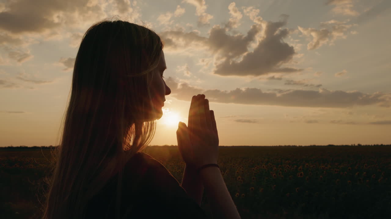 mulher orando em um campo ao pôr do sol