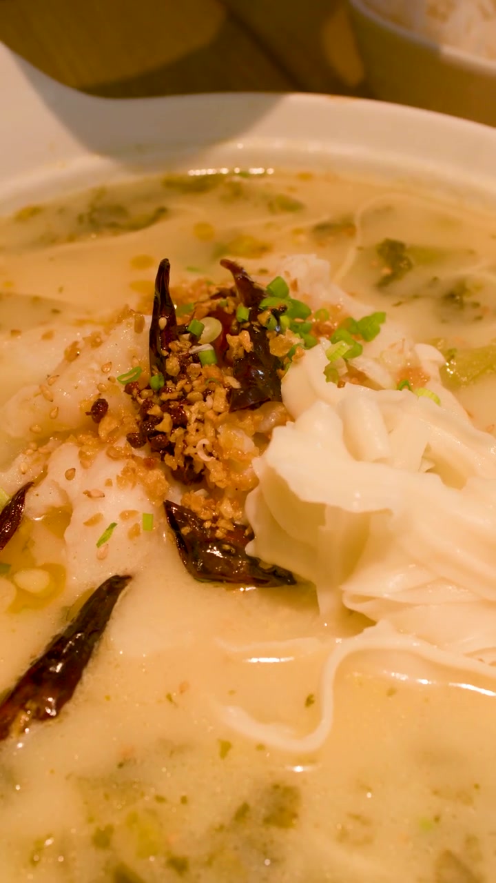 Spiser traditionel kinesisk fiskesuppe med nudler med spisepinde