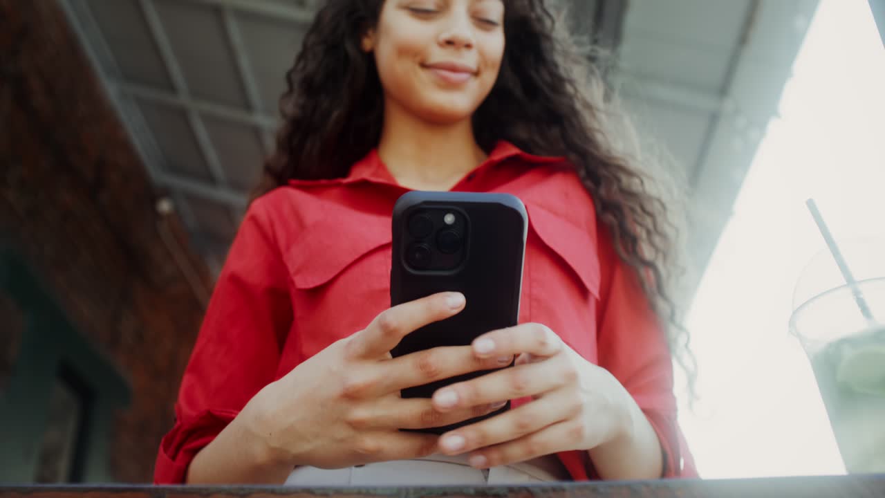 mujer usando el teléfono y bebiendo cócteles afuera