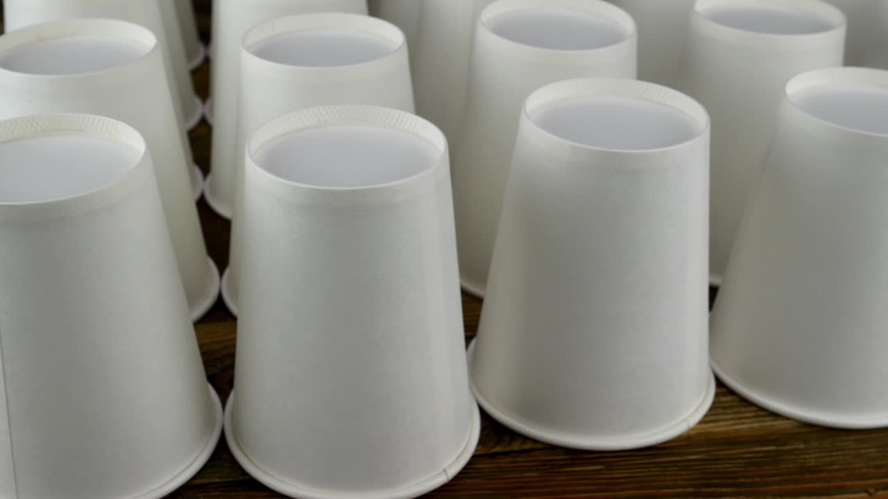 fila de taza de papel blanco desechable para café o bebida caliente en un fondo oscuro girar lentamente.