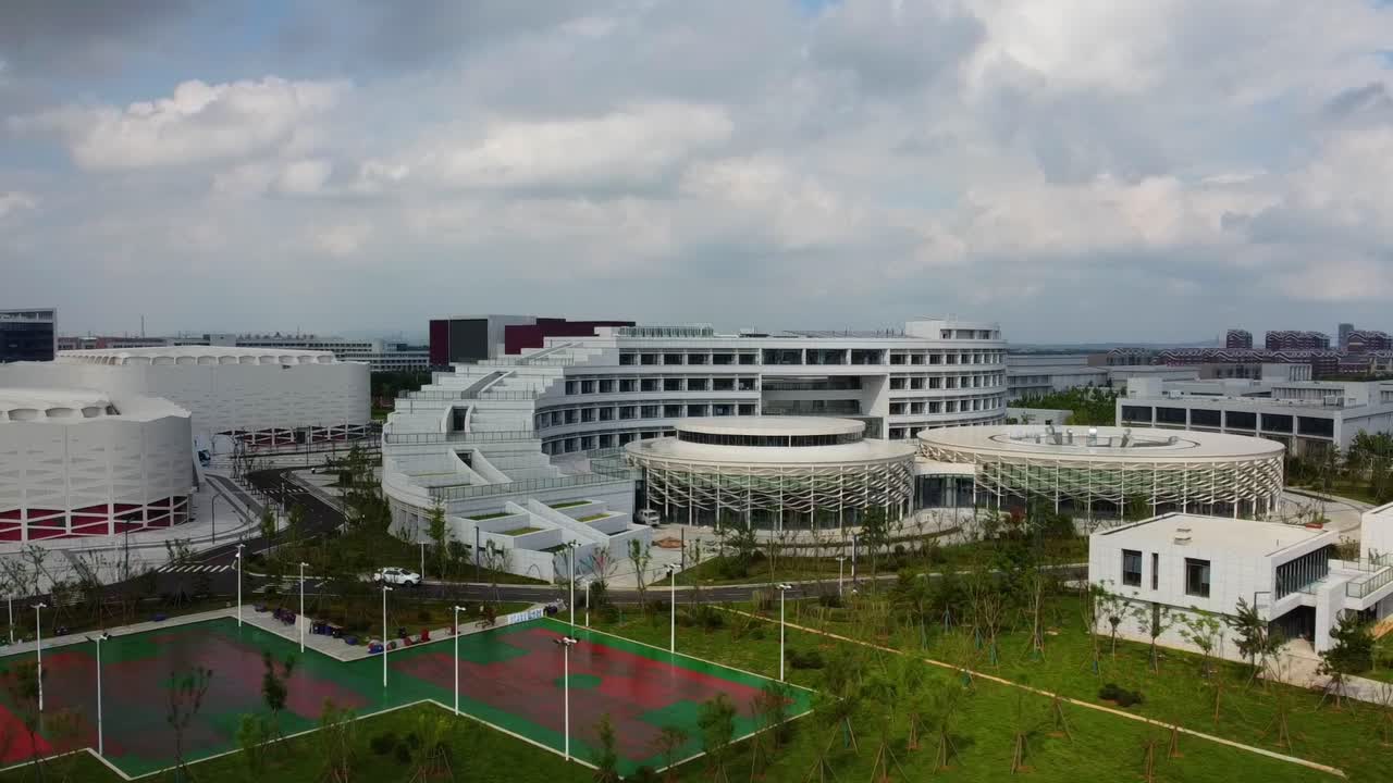 Weihai Olympic center building sliding closeup view showing buildings, car parks, basketball courts, landscape