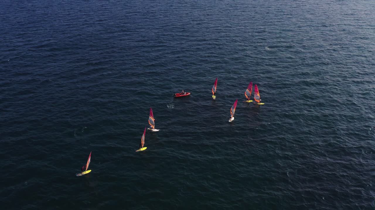 헤르젤리야 근처 지중해의 주황색 스피드보트 주위에 노란색과 흰색 서프보드가 있는 윈드서퍼 그룹