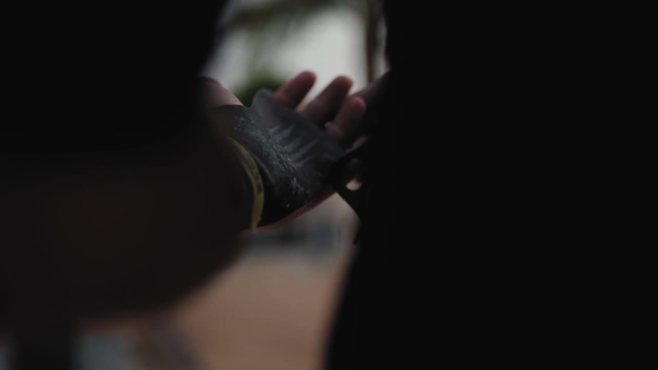 Bodybuilder putting off his sports gloves. Close up.