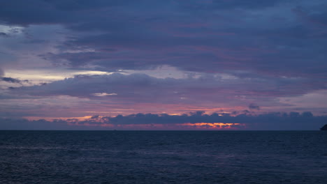 burning sunset sky by the sea with purple pink orange color sunshine reflected in low floating dense fluffy clouds