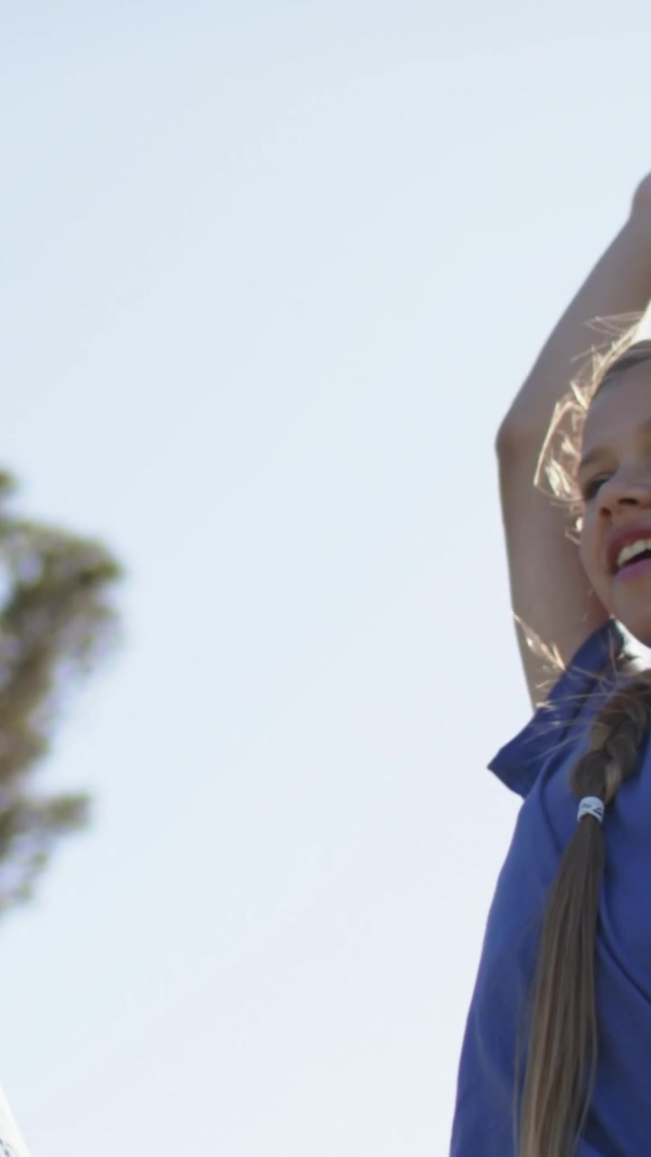Vídeo vertical: Câmera subindo revelando uma menina de camisa azul estendendo a mão e chamando no parque, clipe.
