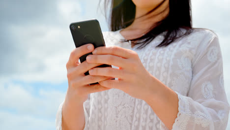 Low-angle-view-of-young-caucasian-woman-using-mobile-phone-at-beach-4k