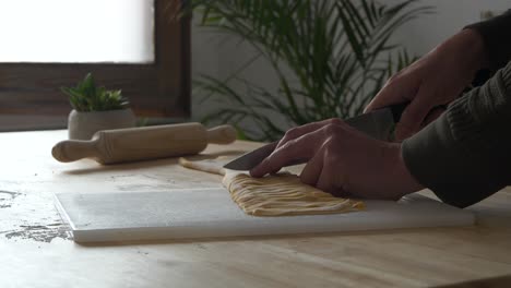 slicing pieces of homemade tagliatelle pasta, close up