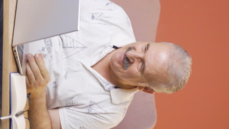 video vertical de satisfecho con lo que ve en la computadora portátil, el anciano asiente.