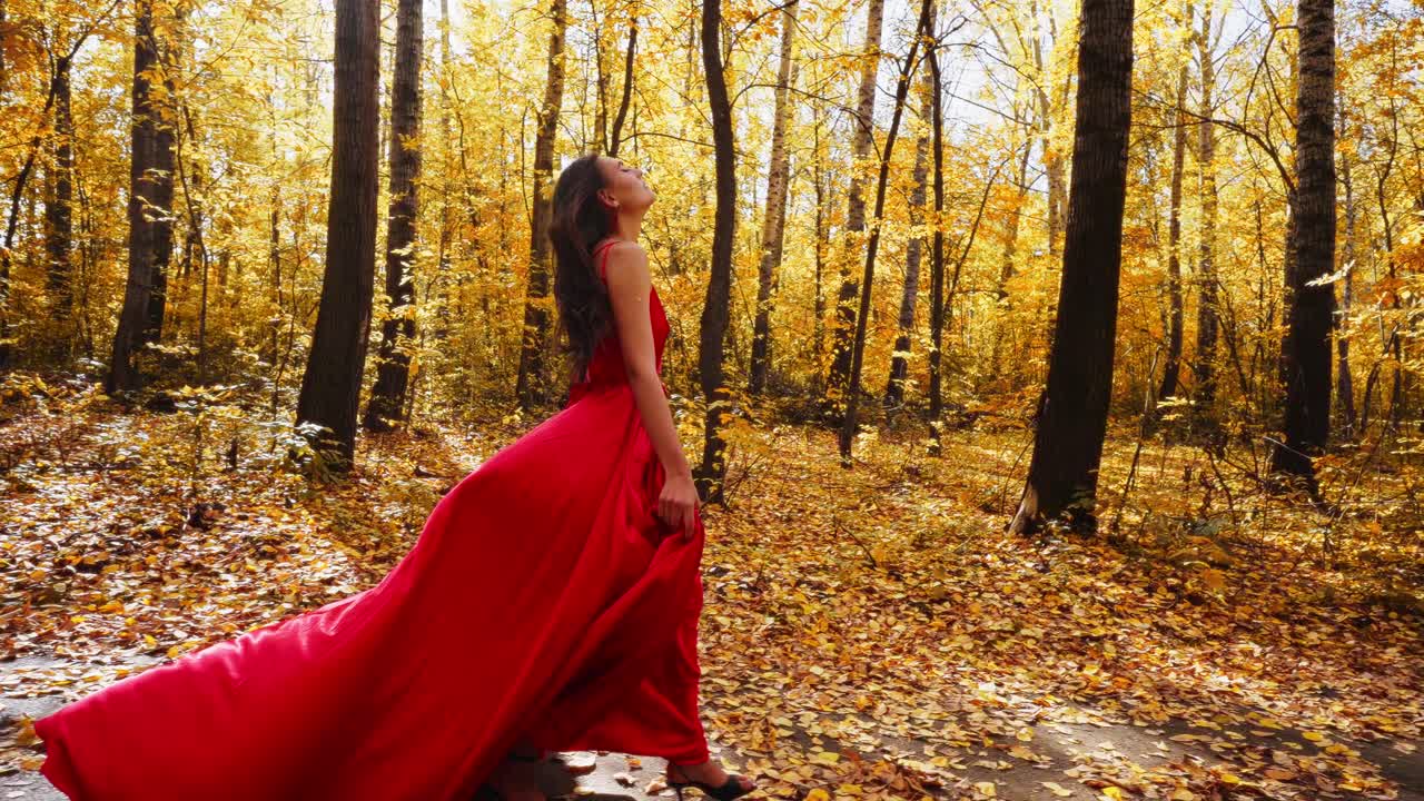 A graceful figure in a flowing red gown strolls through a vibrant autumn forest, surrounded by golden leaves and towering trees, capturing the essence of nature's beauty