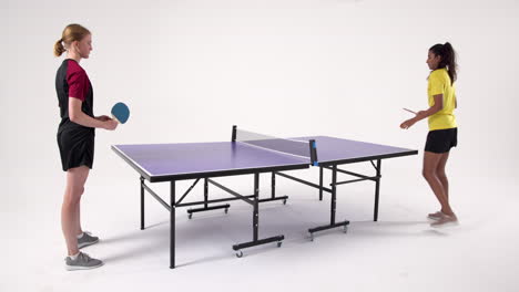 playing table tennis, two women competing intensely in studio setting