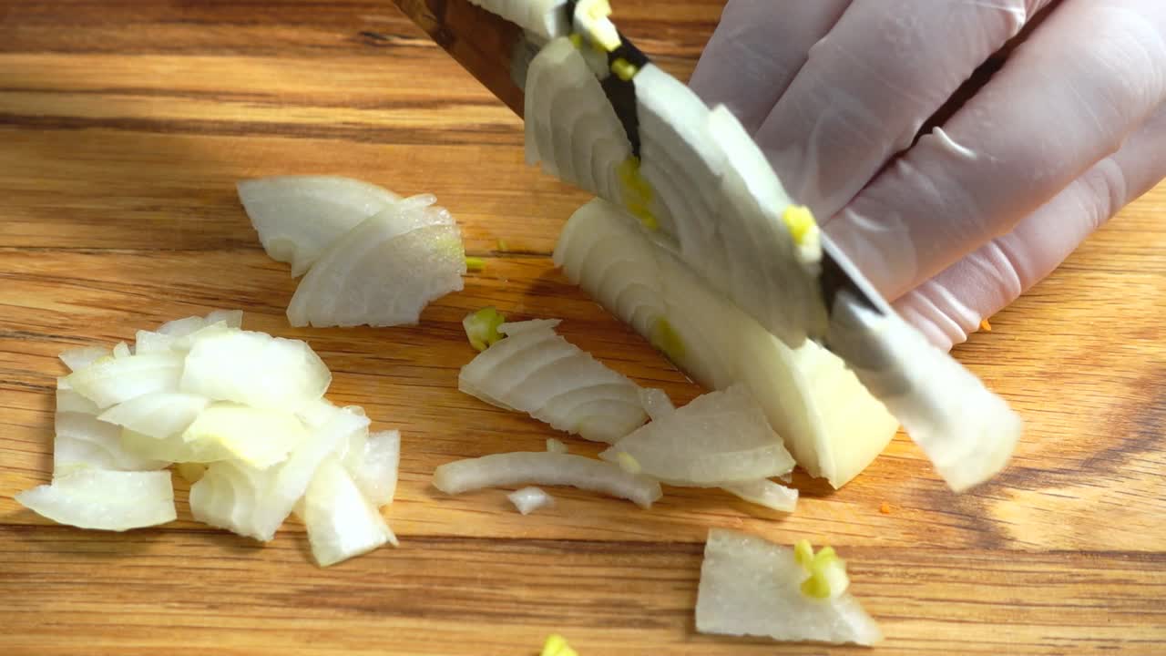 Chef's hands with knife cutting the onion on the wooden board. Preparation for cooking. Healthy eating and lifestyle