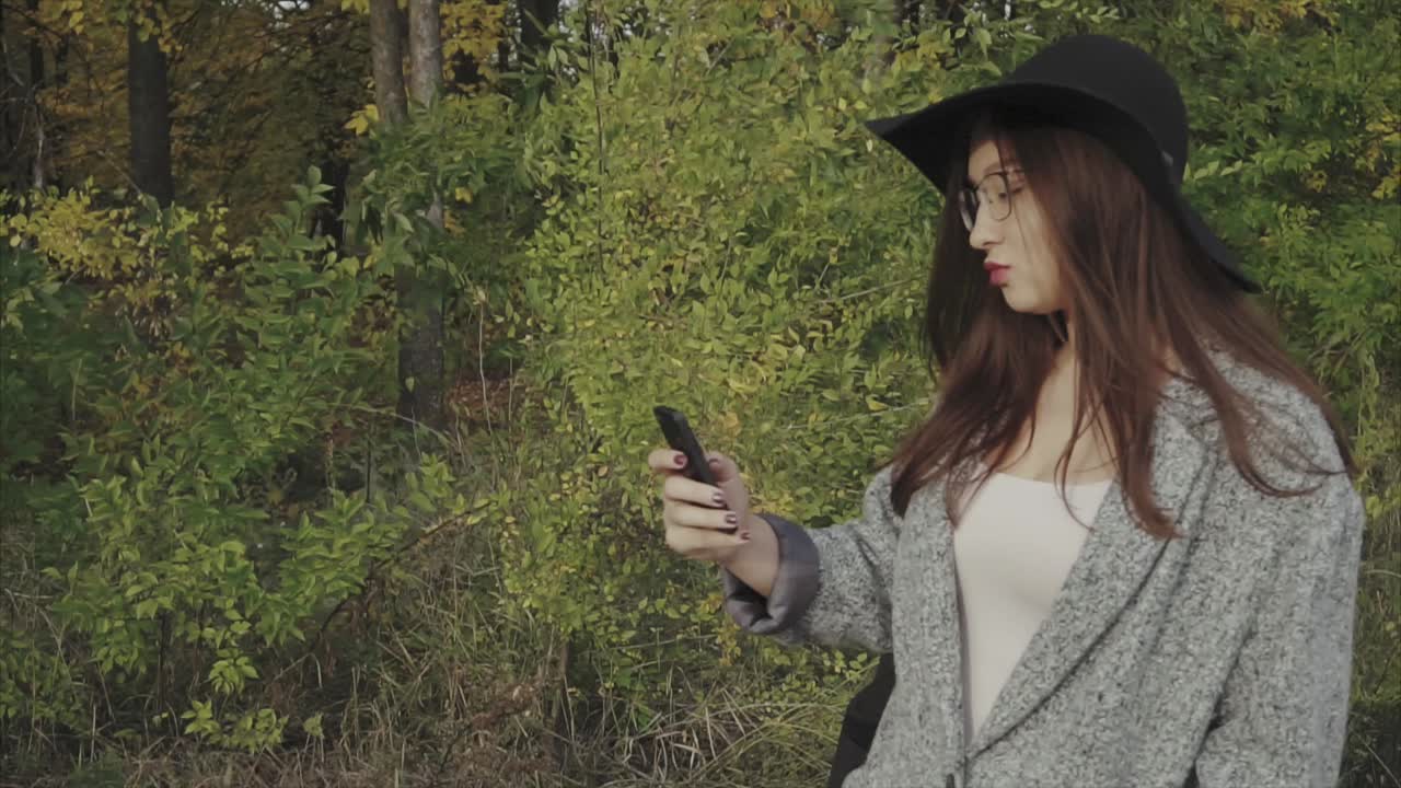 Woman using phone outdoors in fall foliage