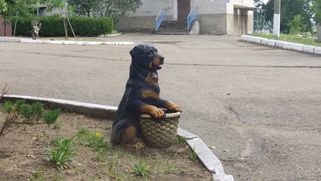 estatuilla artificial de un perro con una canasta en el patio en verano