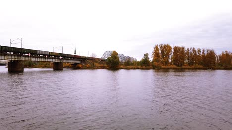 Cargo-train-transporting-wagons-across-the-iron-train-bridge-in-downtown-of-Rige-city,-Latvia