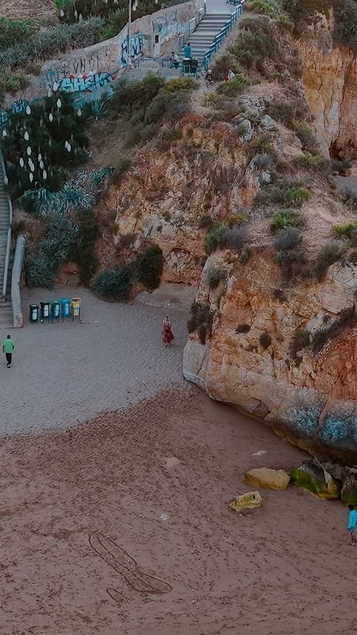 Persone che camminano sulla spiaggia vicino alle scogliere in Portogallo durante il giorno