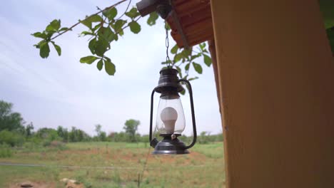 a modern bulb lantern hanging outside a village hut in rural india