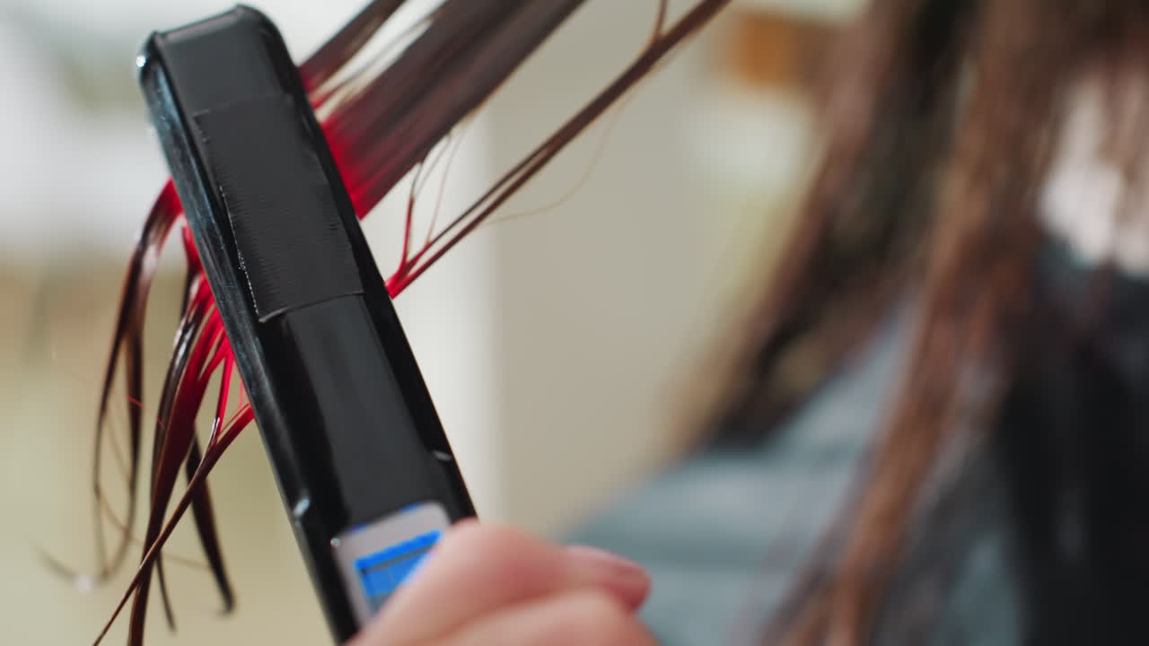 wet hair in salon, stylist demonstrating straightener performance on caucasian woman's mid-lengths, close-up of plates clamping strands and red indicator light, detailed tool demo and glossy result