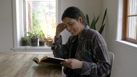 smiling multi-ethnic female sitting reading book relaxed in home interior