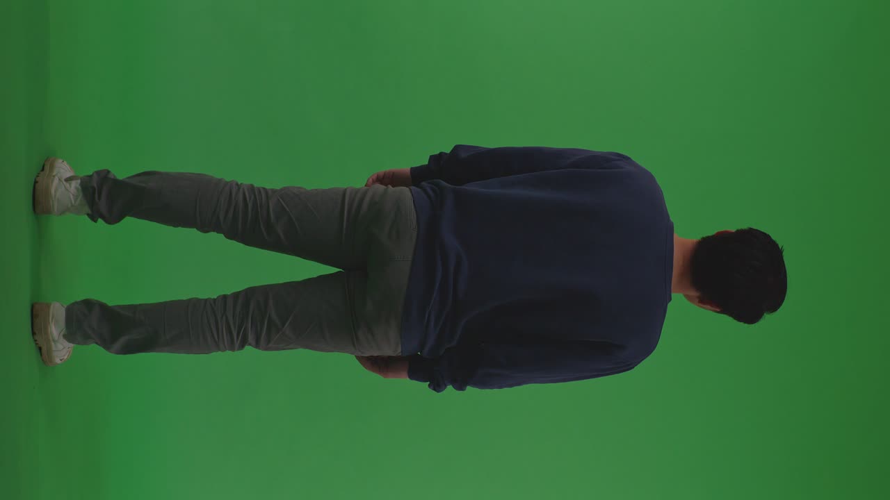 Full Body Back View Of Distressed Asian Refugee Male Standing And Looking Around Protects Himself From The War On The Green Screen Background