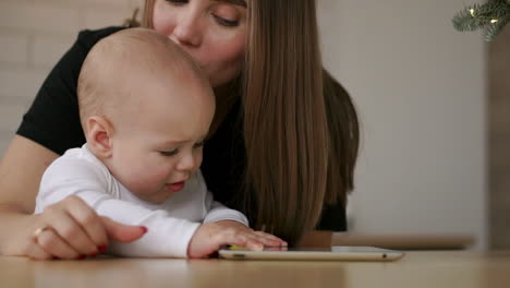 joven madre caucásica usando una tableta con su hijo bebé. cámara lenta 120 fps. madre mostrando a su hijo una tableta digital. niños y concepto de tecnología. niño pequeño. familia cinematográfica