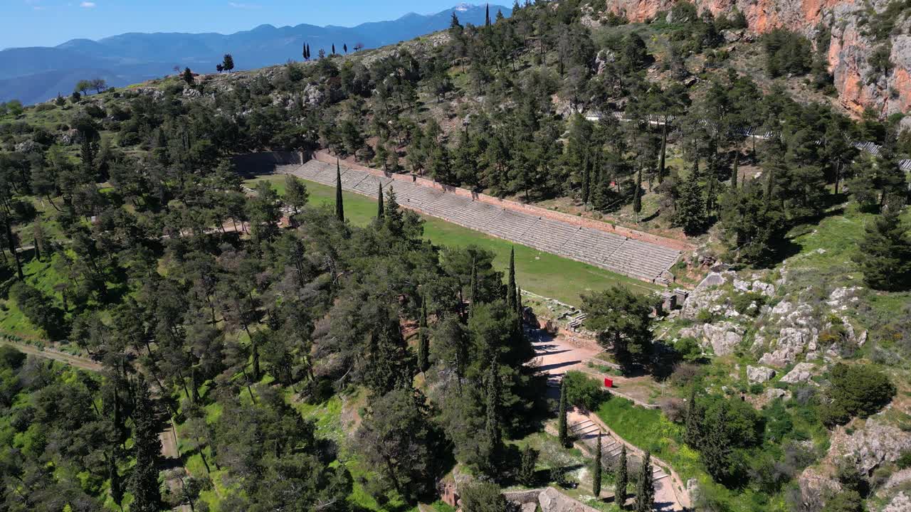 Aerial flyover of Delphi stadium establishing track outline and forested mountains of Greece