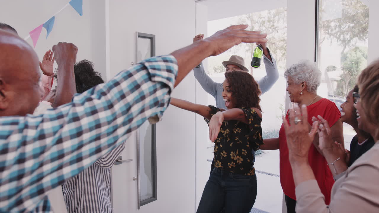 um jovem casal de raça mista é bem-vindo quando chegam com champanhe para uma festa familiar.