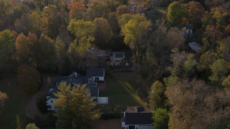 tilt-down-and-hover-over-a-nice-house-amongst-lush-trees-at-sunset