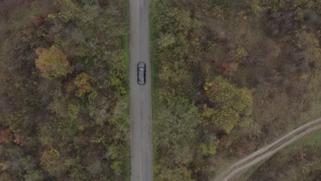 retreating follow-through drone shot of a moving vehicle on a road located at the foot of the balkan mountains in bulgaria