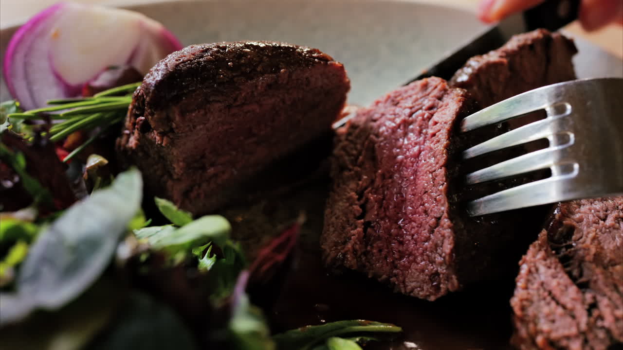 Close up of a filet mignon with a red wine sauce and a fresh salad garnish