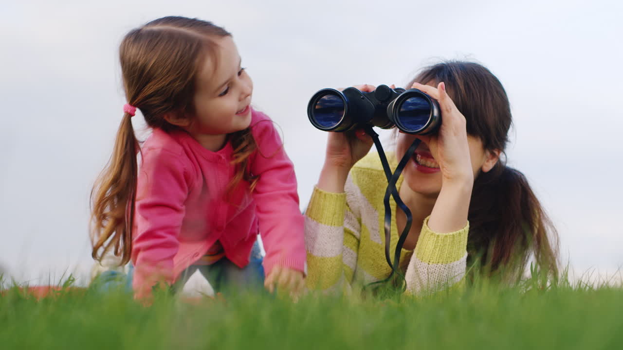 한 젊은 가족이 봄 정원에서 함께 시간을 보낸다 엄마는 쌍안경으로 먼 곳을 바라본다
