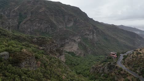 aerial flies through occasional rain drops over rugged forested canyon