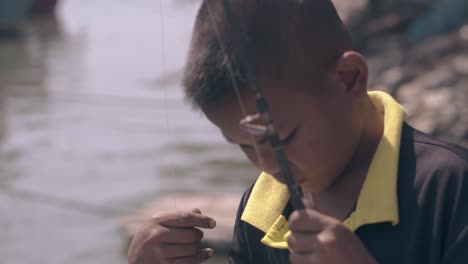 Asian-boy-in-black-t-shirt-prepares-fishing-rod-in-bay