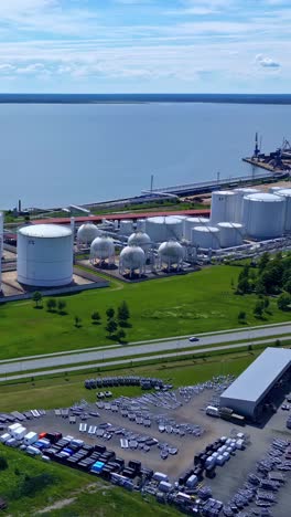 an industrial area with storage tanks and a harbor in the background, aerial view