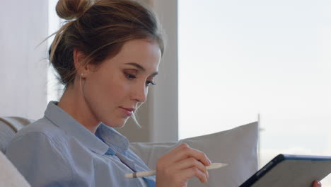mujer joven atractiva usando una tableta digital trabajando en casa navegando por mensajes de correo electrónico con lápiz stylus disfrutando de la tecnología de dispositivos móviles