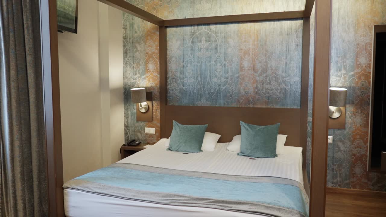 Hotel room with four-poster bed, teal accents, and artistic wallpaper