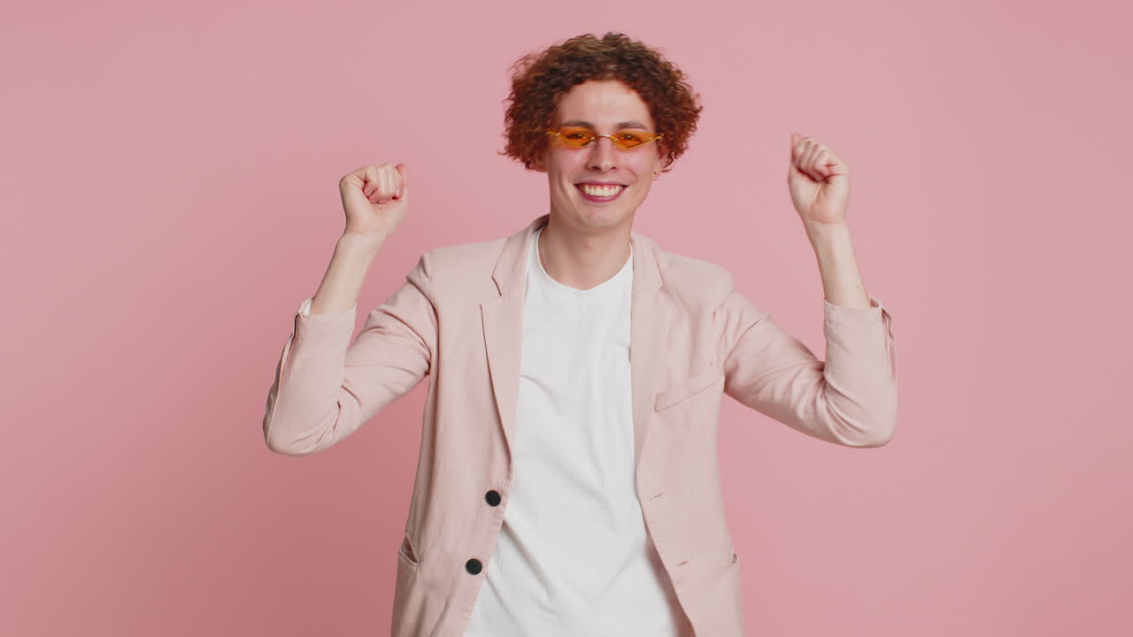 Homem com cabelo encaracolado ouvindo música dançando discoteca brincando se divertindo em fundo rosa