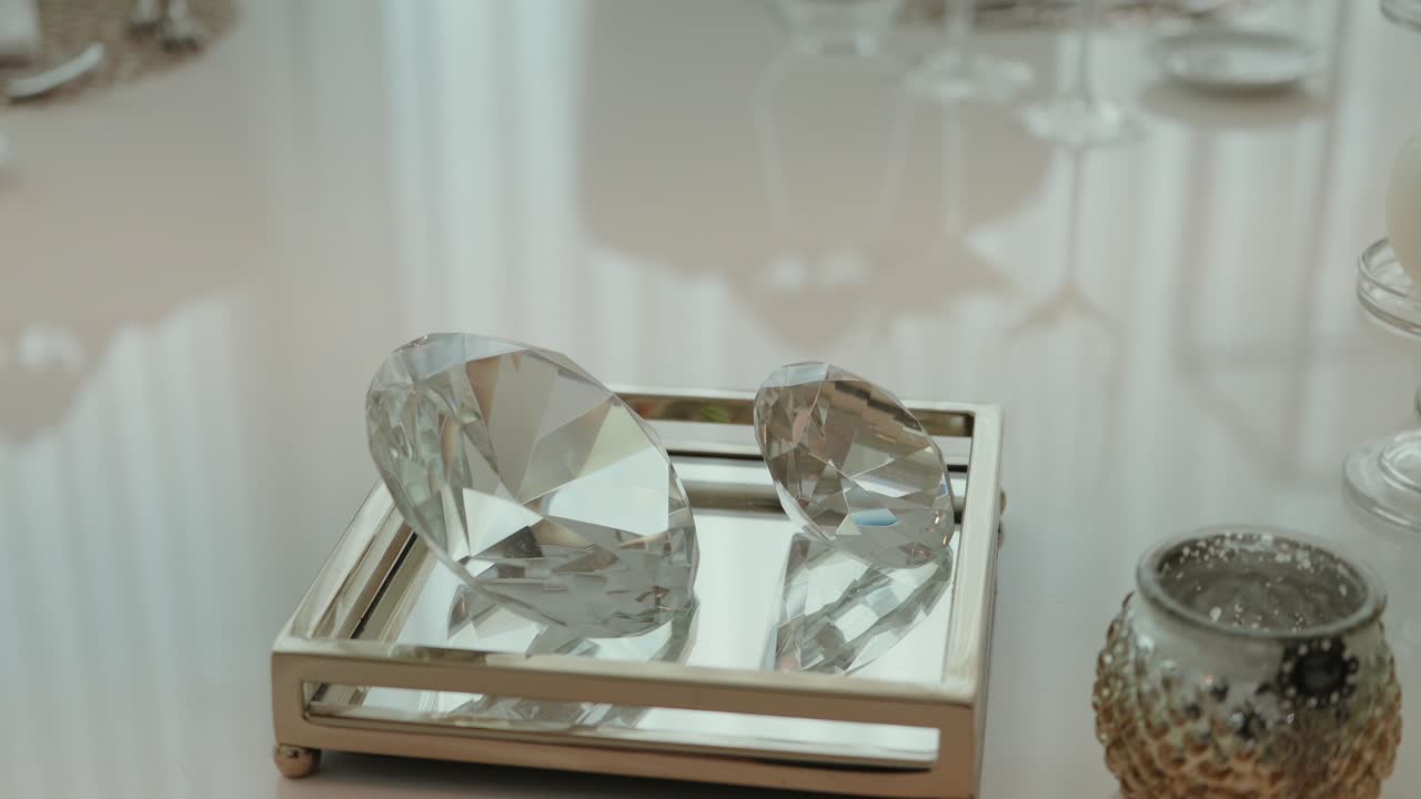two faceted glass gems placed on a silver mirrored tray with soft lighting and luxury ambiance
