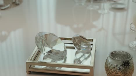 two faceted glass gems placed on a silver mirrored tray with soft lighting and luxury ambiance