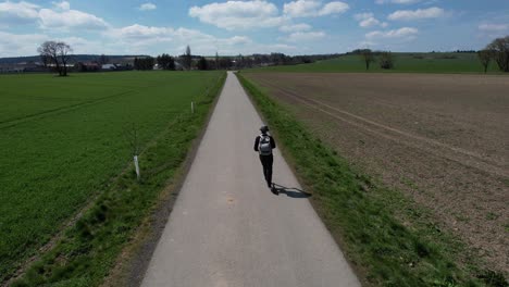 overhead view of man riding an eletric scooter on a scenic rural road, near svitavy in the czech republic