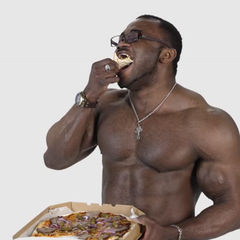 black man enjoys eating pizza. portrait of a muscle sportsman with black skin eats tasty pizza on white studio background. unhealthy food