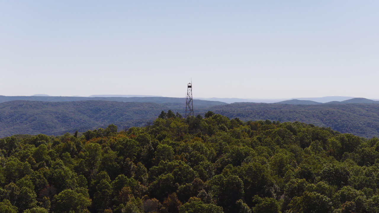 Torre di avvistamento antincendio Devils Knob sopra una fitta foresta verde circondata da montagne in Arkansas. Ampia ripresa aerea con drone