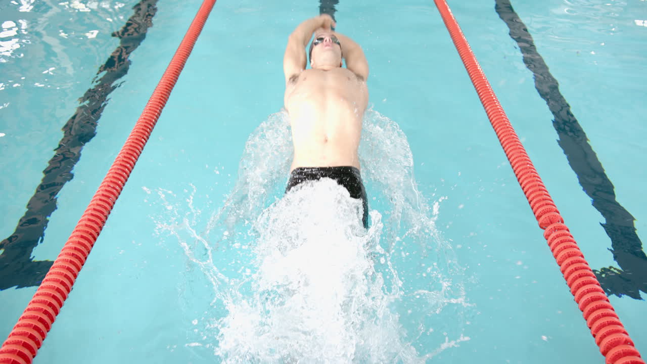 Swimming in lane, male athlete making powerful strokes in competitive pool