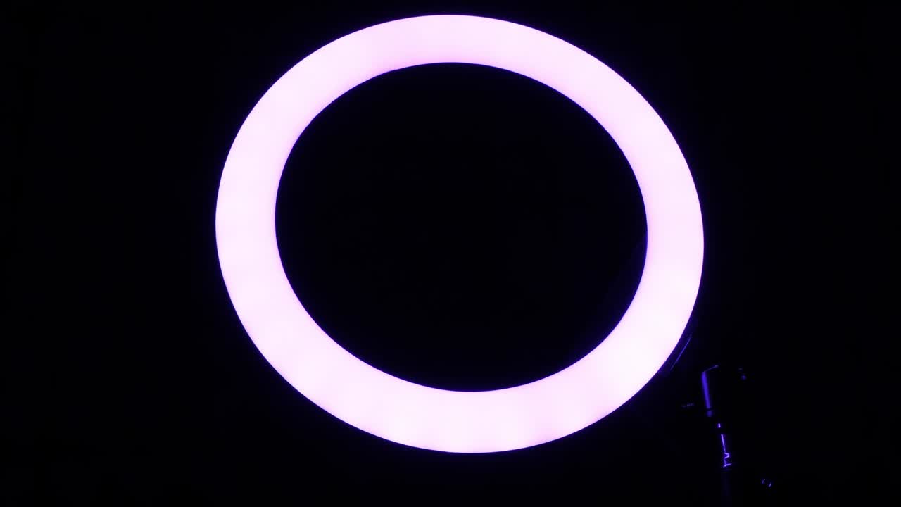 Luminous ring rgb lamp. Multicolored light in a dark room, close-up.