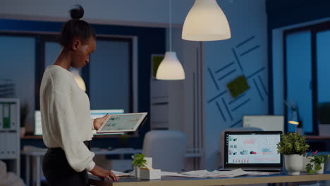 Black-woman-employee-standing-in-office-and-analysing-charts