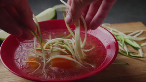 putting fresh zucchini noodles into hot paleo chicken broth soup