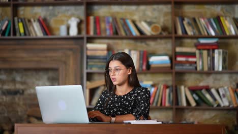 mujer trabajando en una computadora portátil en una biblioteca