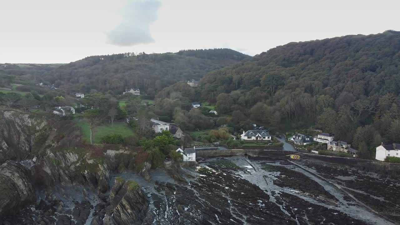 órbita aérea de un pequeño pueblo costero en un valle en un día nublado - bahía de lee, playa, ilfracombe, devon, inglaterra