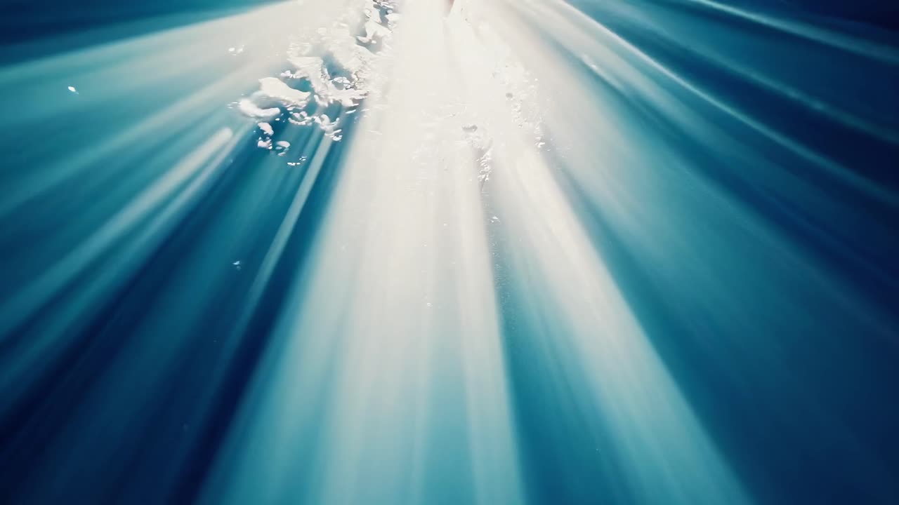Underwater video scene with beams of light piercing through bubbles, captured from a low angle